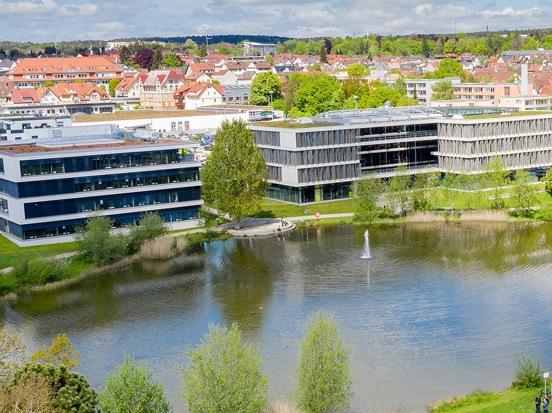Bild mit See im Vordergrund und im Hintergrund die Zentrale der vivida bkk sichtbar