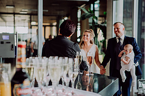 Junges Hochzeitspaar mit Sektgläsern im Vordergrund