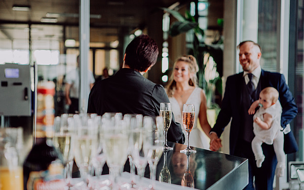 Junges Hochzeitspaar mit Sektgläsern im Vordergrund