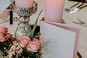 Tischdeko aus zwei Kerzen mit Blumen